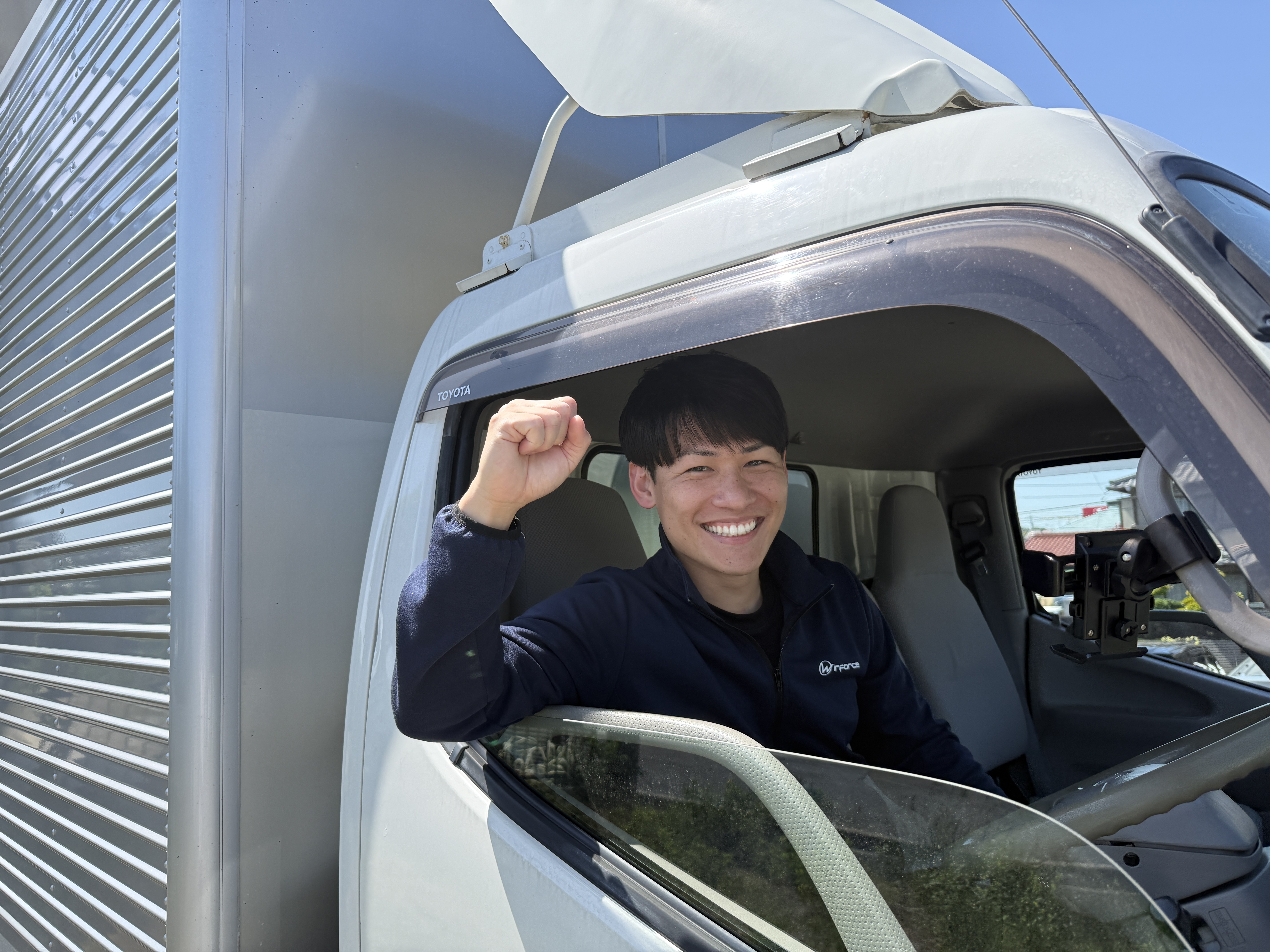 トラックの運転席から笑顔のWinforceスタッフ